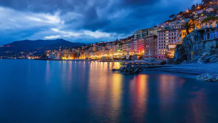 HD wallpaper of a coastal city in Liguria, Italy, showcasing man-made structures with vibrant lights reflecting on calm waters under a dramatic evening sky.