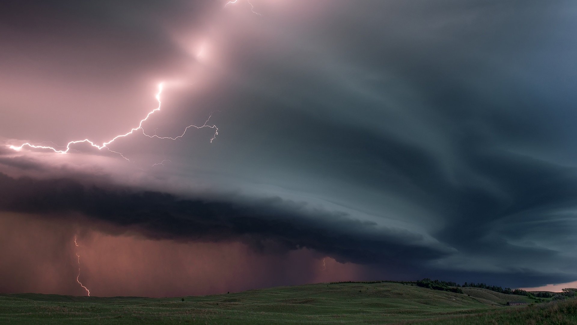 HD desktop wallpaper showing a stormy sky over a field with dark clouds and bright lightning illuminating the scene.