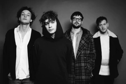 Black and white HD wallpaper featuring The 1975, showcasing the band members in a stylish pose against a simple backdrop, capturing their unique aesthetic and vibe.