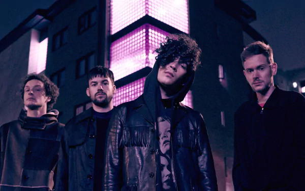 HD desktop wallpaper featuring The 1975 band members standing together at night with urban lighting in the background.