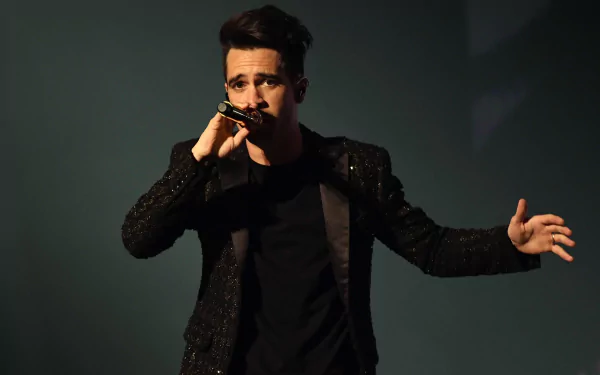 HD wallpaper of a band's lead singer performing onstage, microphone in hand, evoking the energetic style of Panic! at the Disco.